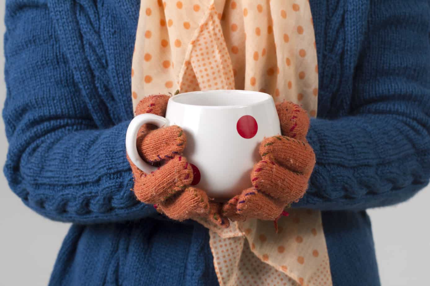 A person holding a hot cup of cocoa with winter gloves