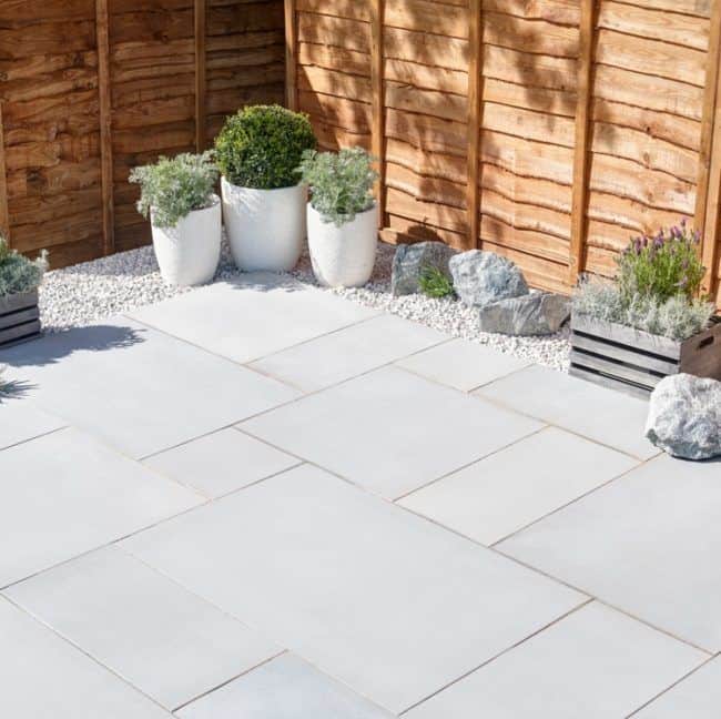 White sandstone patio garden deck decorated with plants and wooden fencing