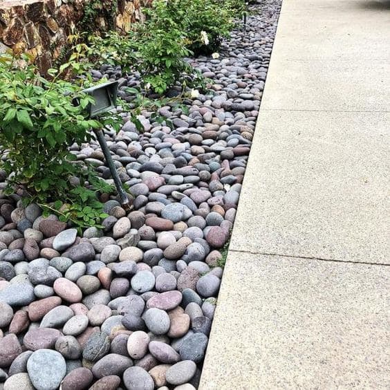 Simple, grey pebbles as an attractive base for a flower bed