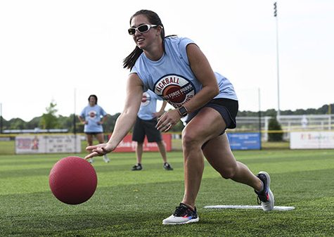 A woman rolling a pitch during a kickball game