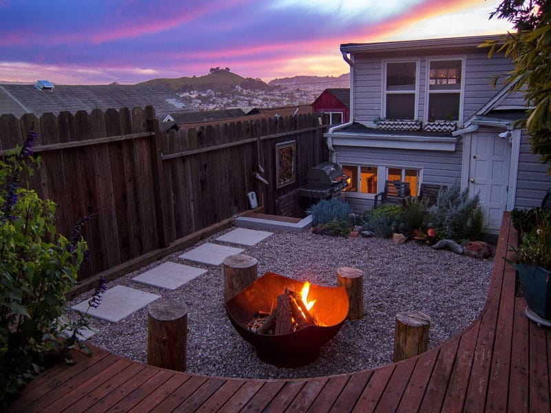 Upper level backyard deck with fire pit and wooden stools