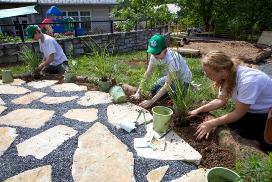 People making stepping stones near a vegetable garden