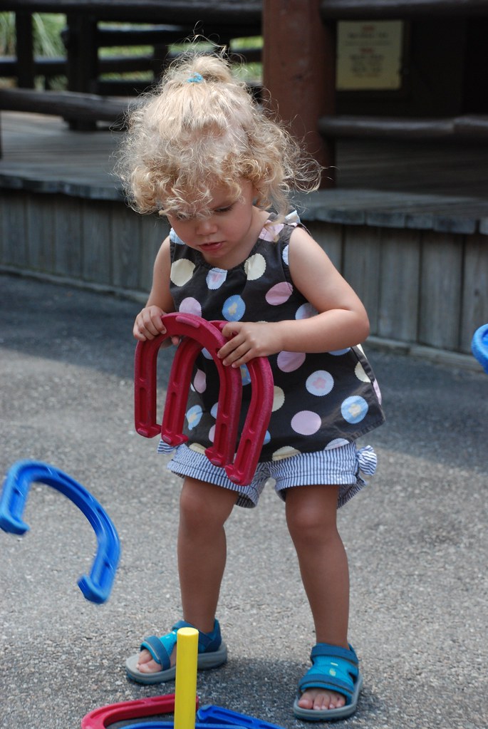 A kid playing horseshoes game outdoors