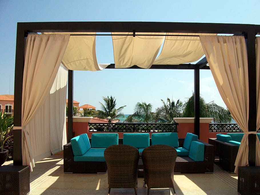 Rooftop pergola draped with white curtains and furnished with an outdoor sofa set